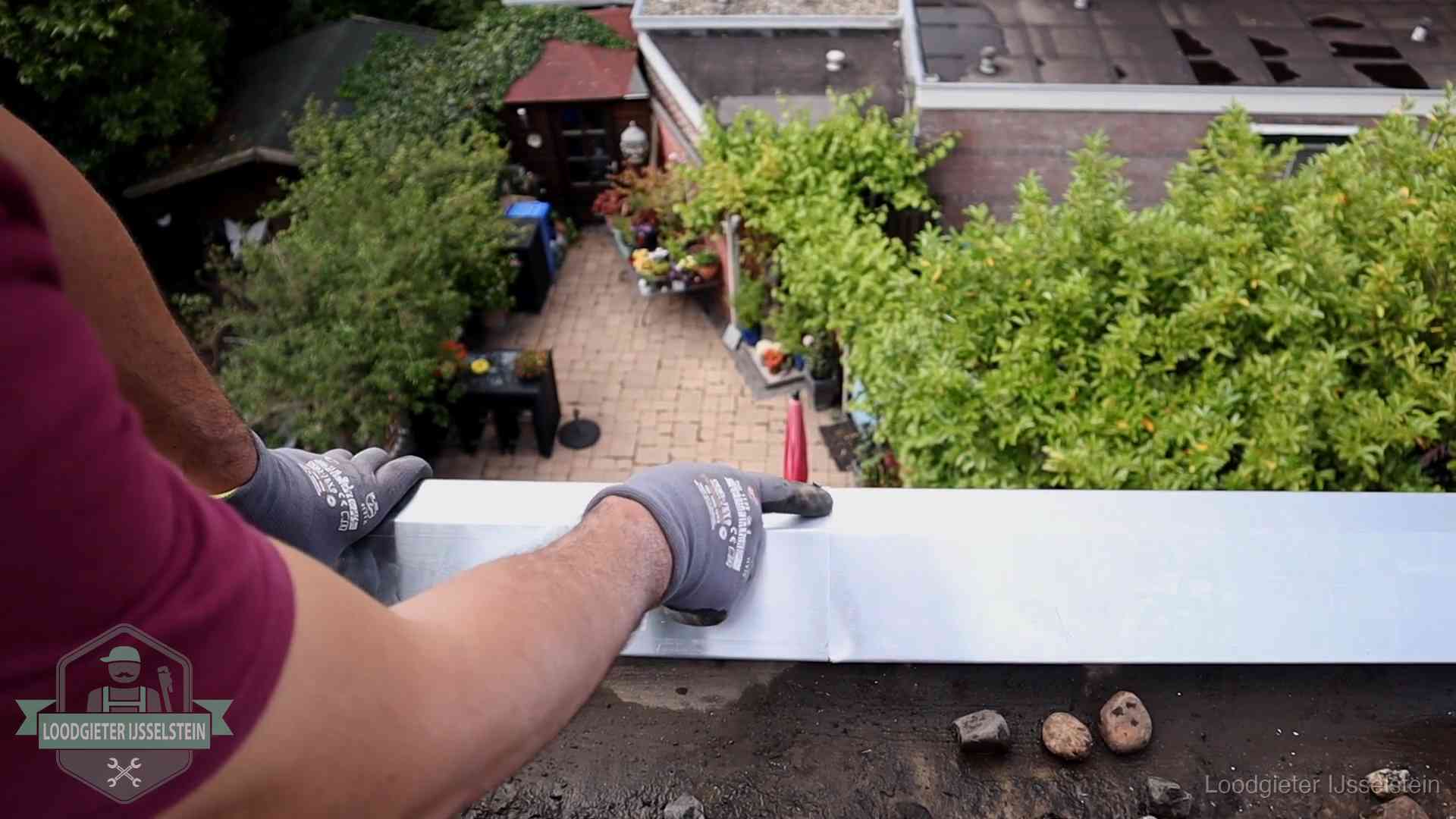 Vakman plaatst een daktrim op de dakrand van een woning in IJsselstein