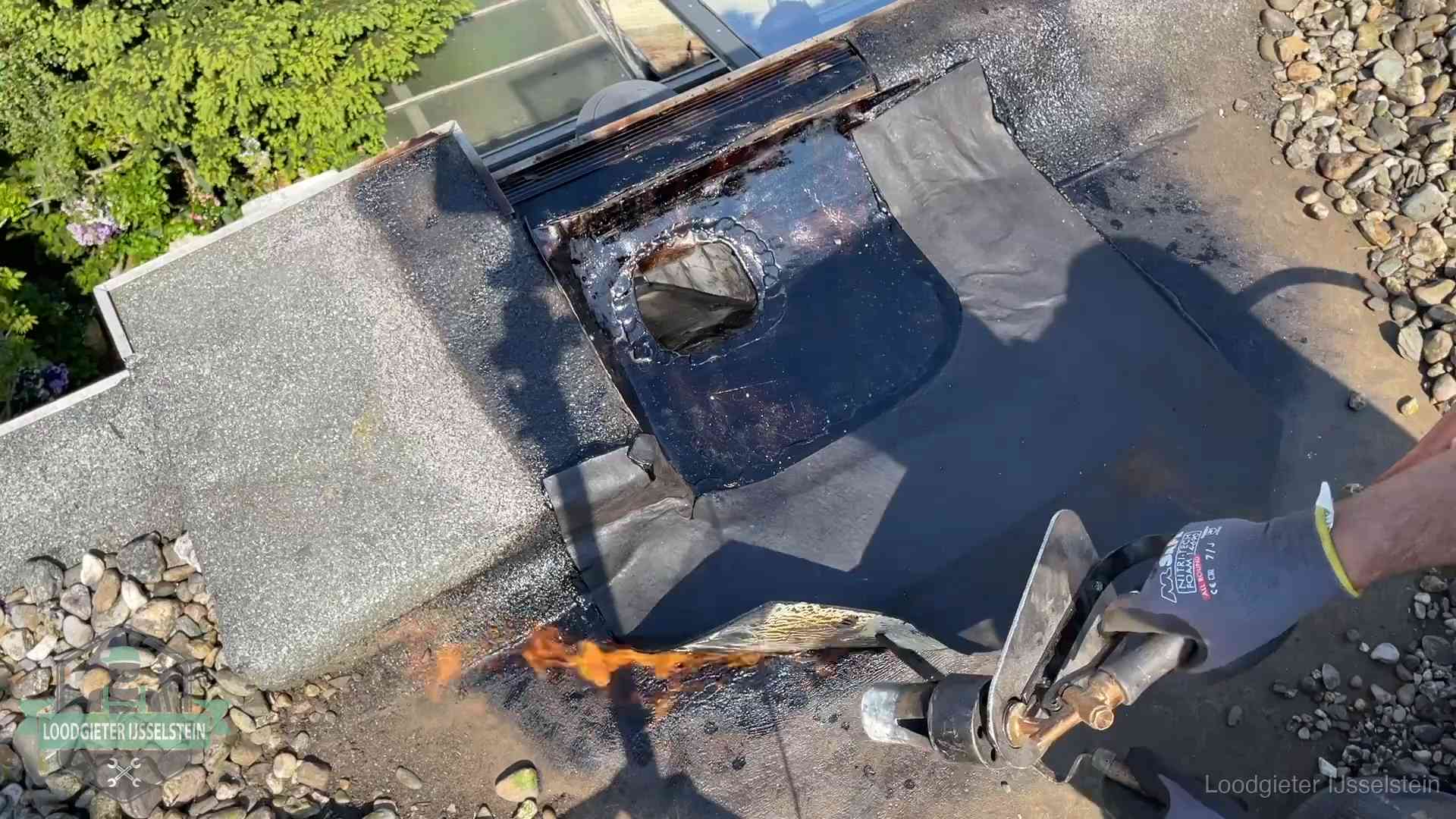 Dakdekker brandt bitumen rond een doorvoer tijdens een daklekkage-reparatie in IJsselstein