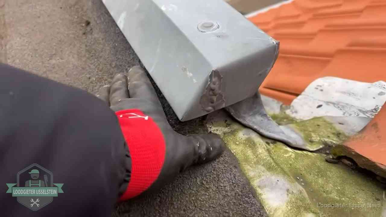 Controle van een zinken hemelwaterafvoer met loodslab bij dakpannen in IJsselstein