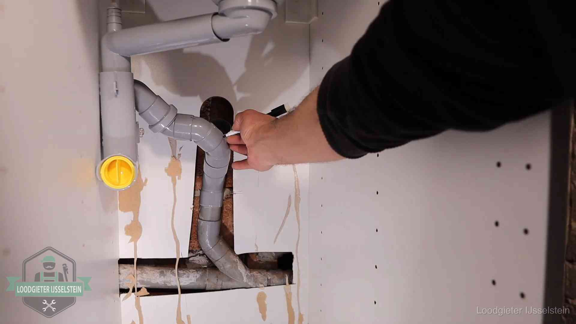 Loodgieter voor verhuurders en bedrijven in IJsselstein Loodgieter markeert een pvc-afvoerbuis onder een gootsteen in IJsselstein