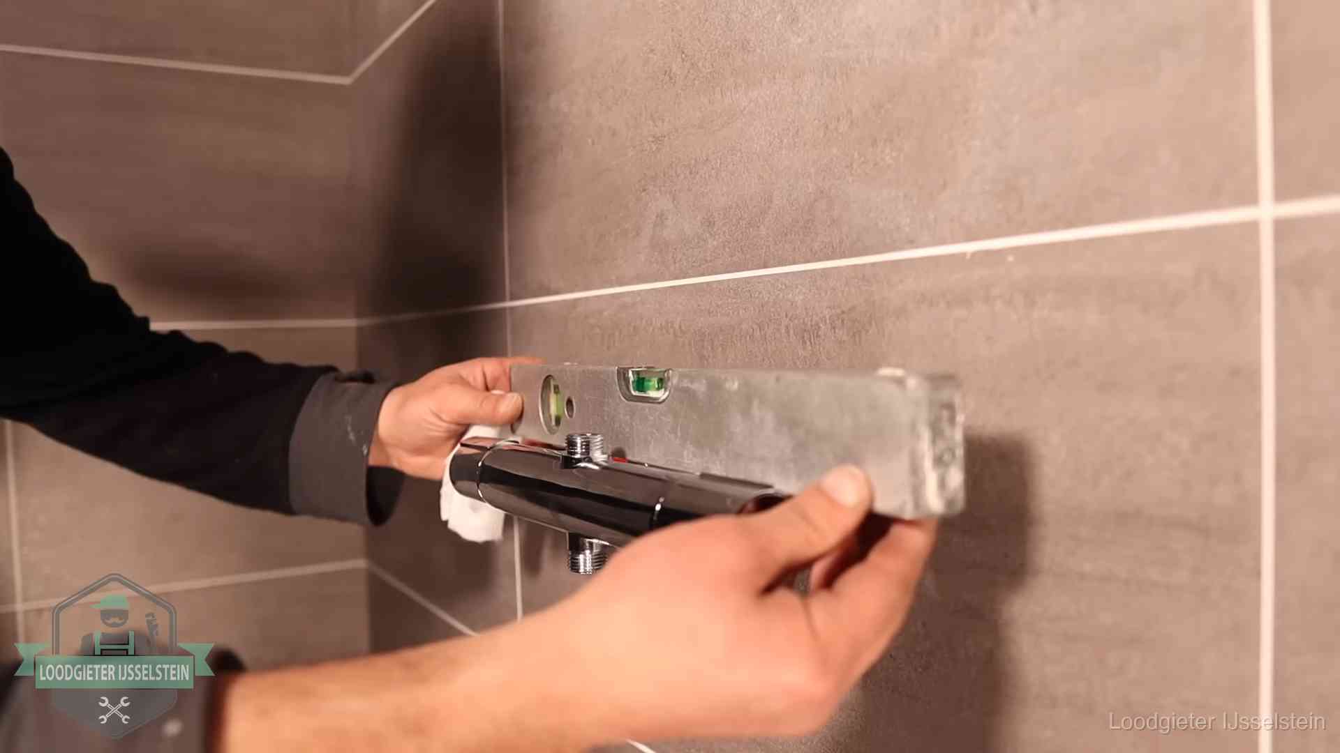 Loodgietersbedrijf voor sanitair in IJsselstein Loodgieter lijnt een douchekraan uit met een waterpas in een woning in IJsselstein