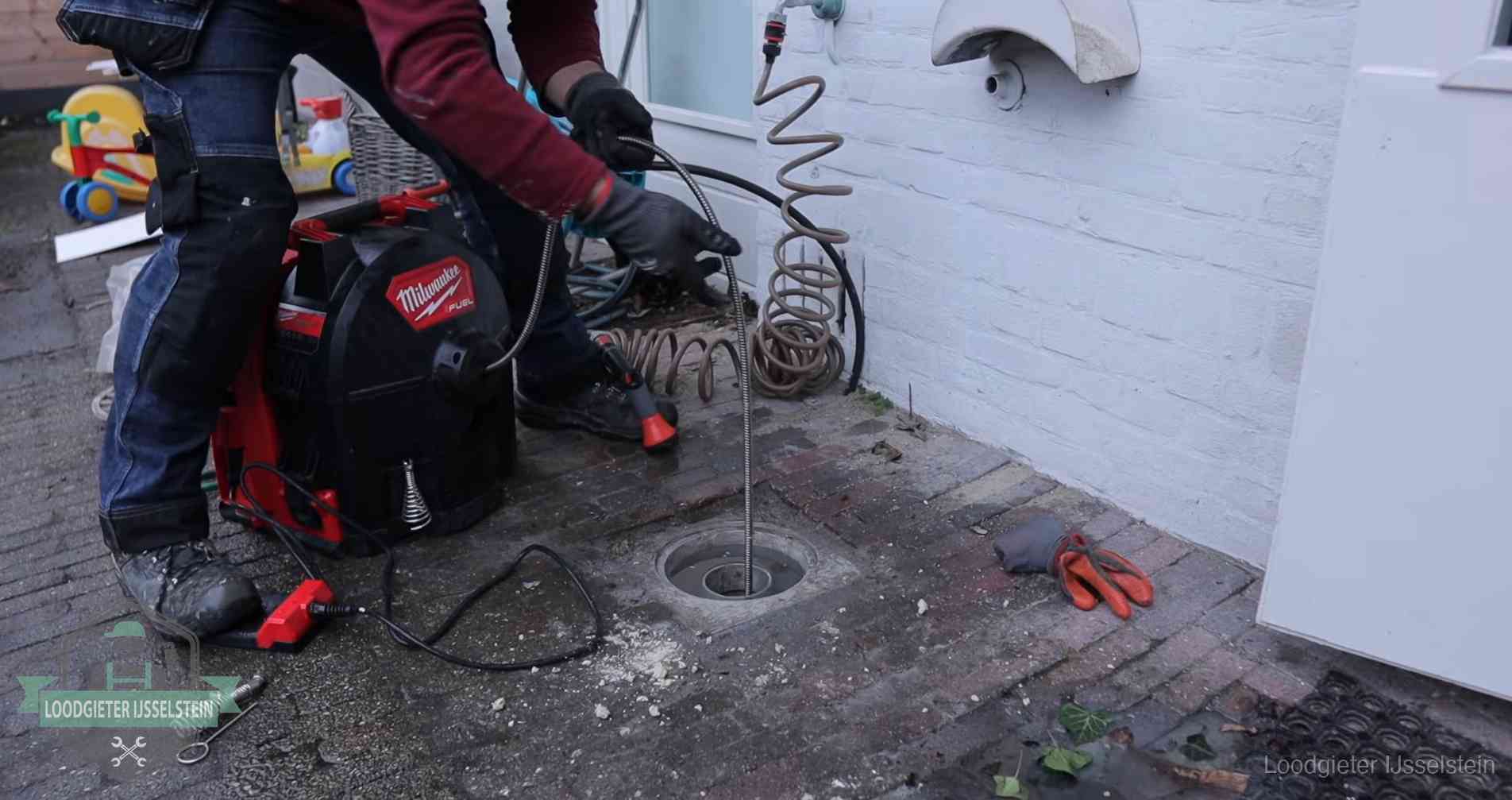 Ontstoppingsputje in de bestrating naast de gevel van een woning in IJsselstein