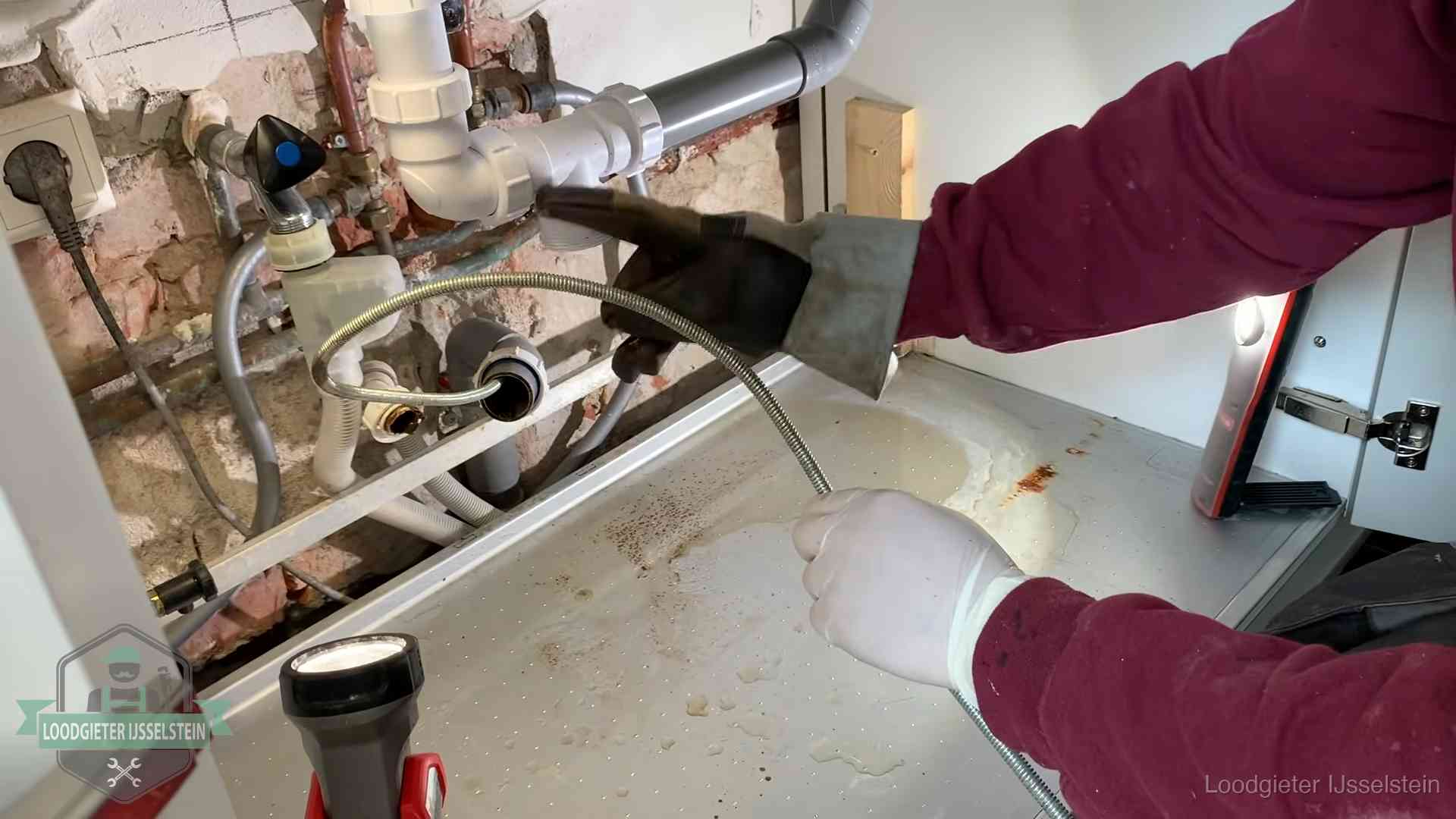 Ontstoppingsveer gaat in een geopende sifonaansluiting onder het aanrecht in IJsselstein