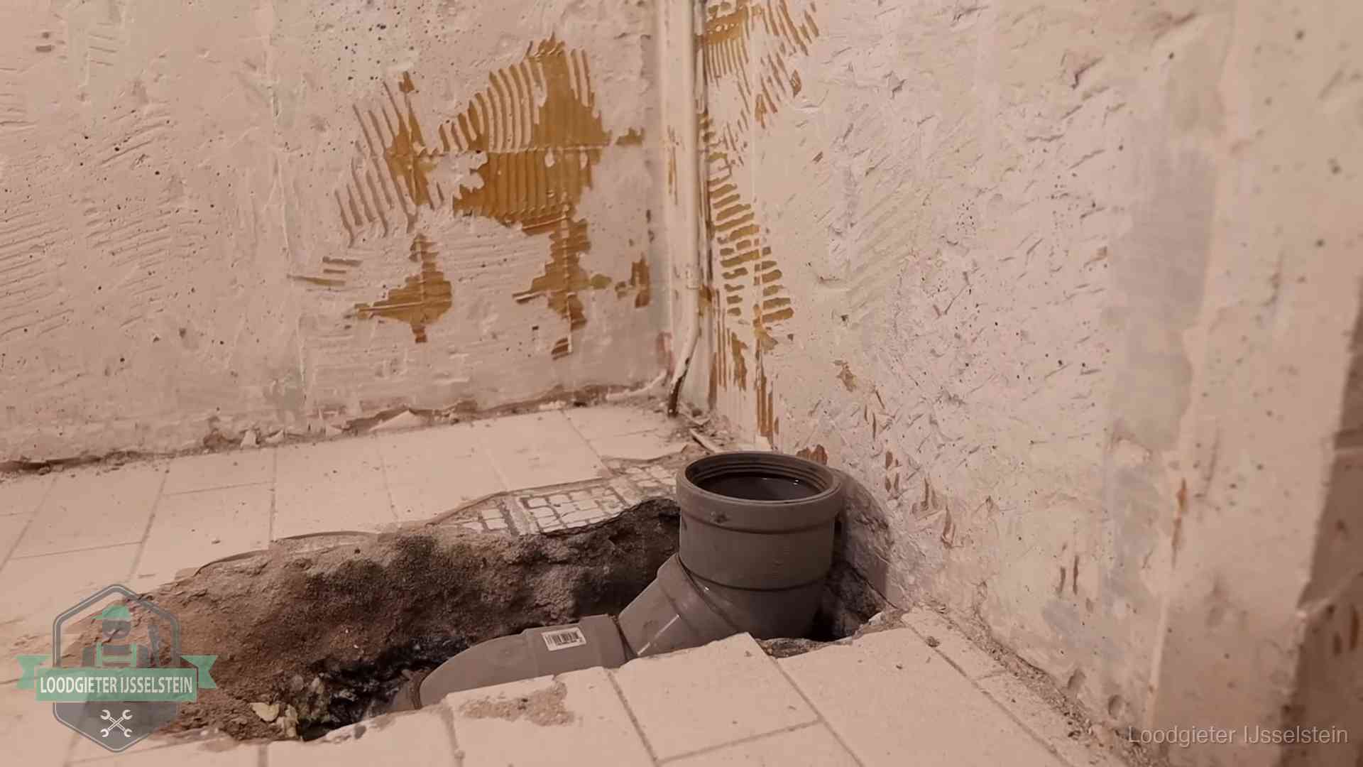 Opengebroken vloer met een nieuwe pvc-rioolbocht in een gegraven sleuf in IJsselstein