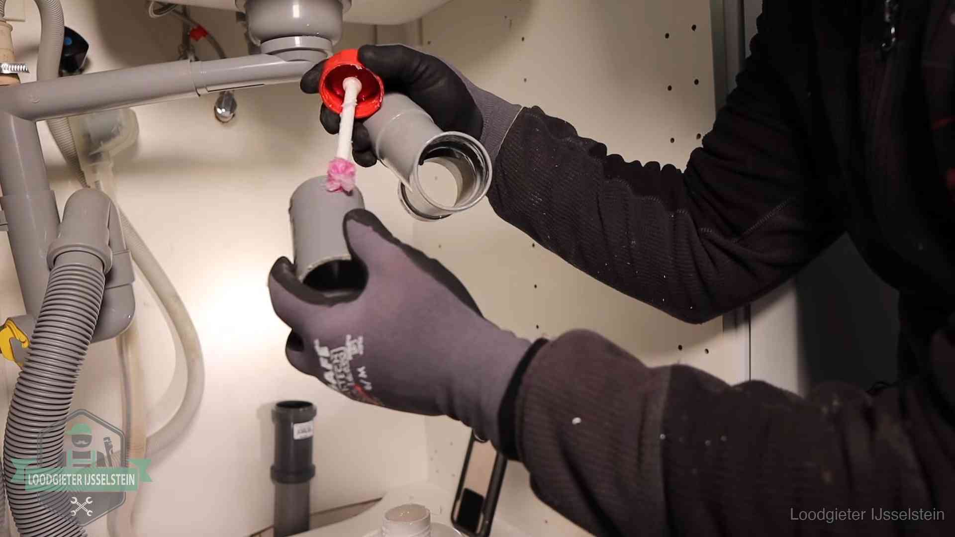 Loodgieter demonteert en reinigt de sifon onder een keukenkast in IJsselstein