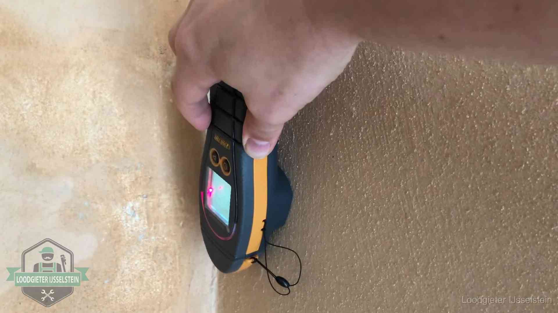 Vochtmeter tegen een muur met vochtplekken tijdens het opsporen van een daklekkage in IJsselstein